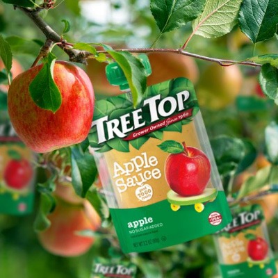 Tree Top apple sauce pouch alongside apples in an apple tree.
