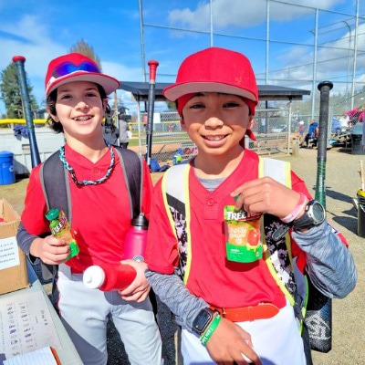 Two kids playing baseball holding Tree Top apple sauce pouches